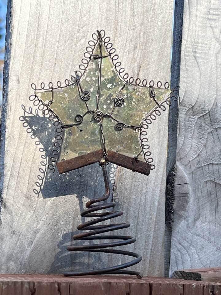 a metal star on top of a piece of wood next to a wire and wooden fence