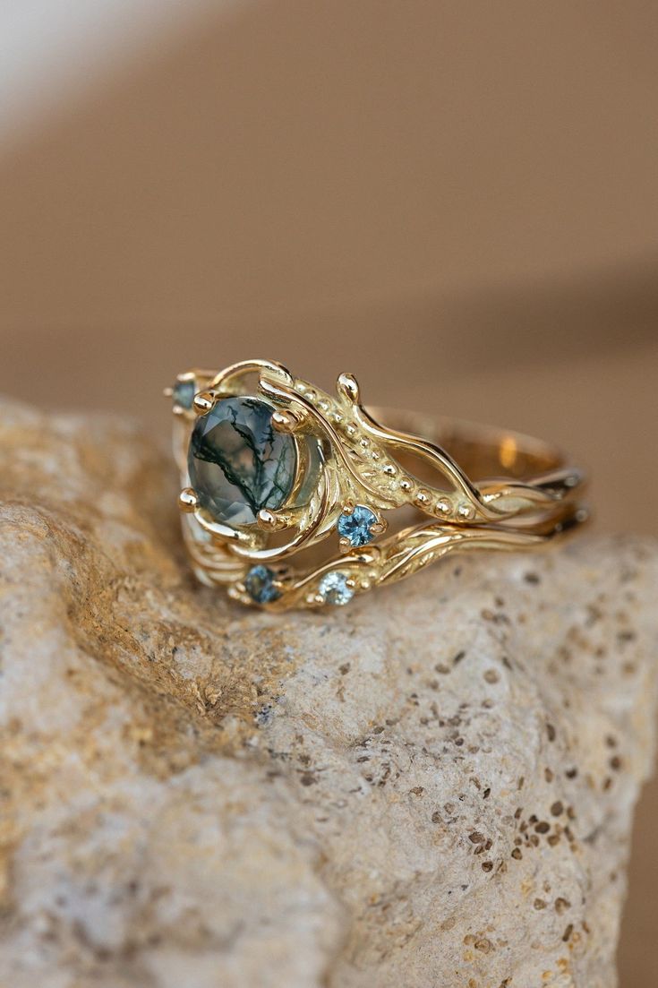 a close up of a ring on top of a rock with blue stones in it