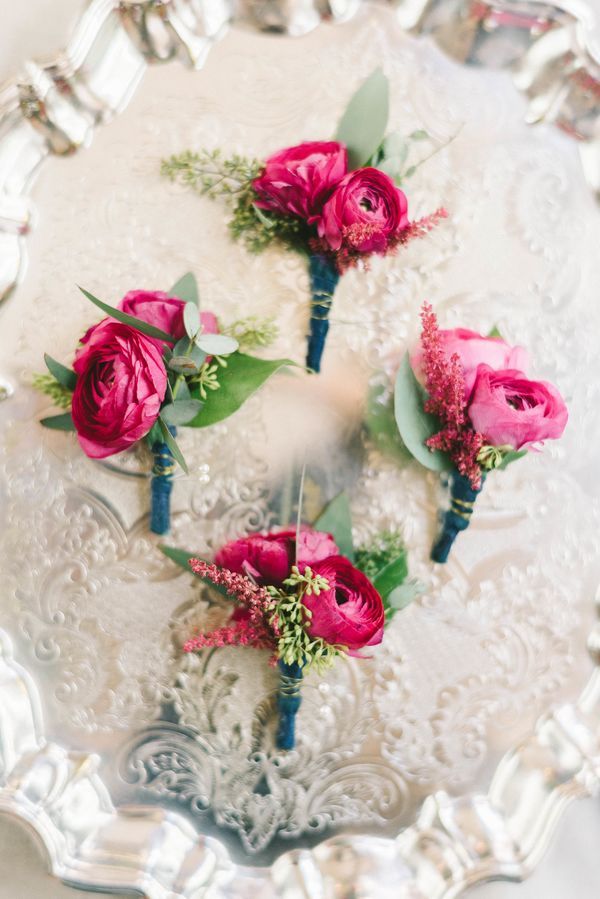 four pink flowers are placed on a glass platter with greenery and silverware