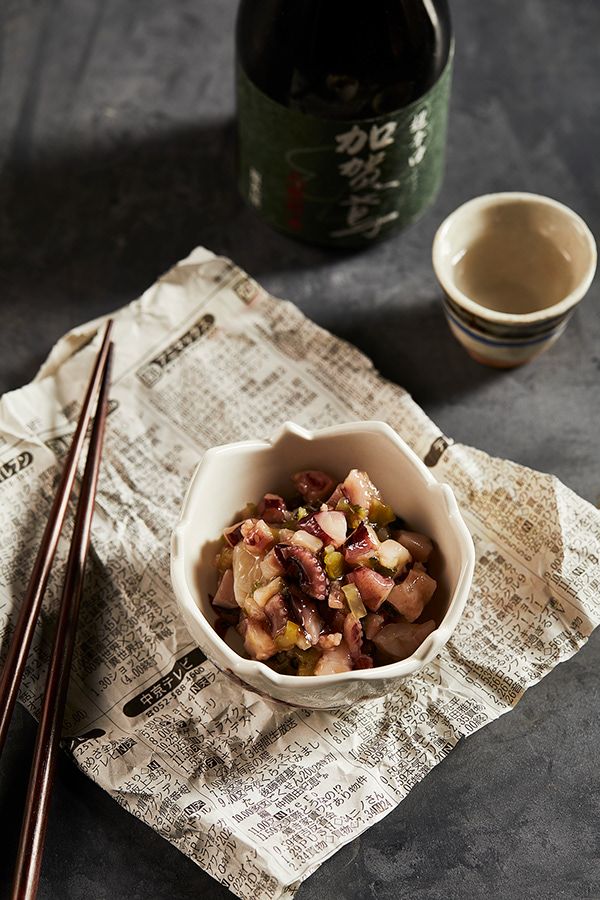 a bowl of food with chopsticks next to it and a bottle of wine