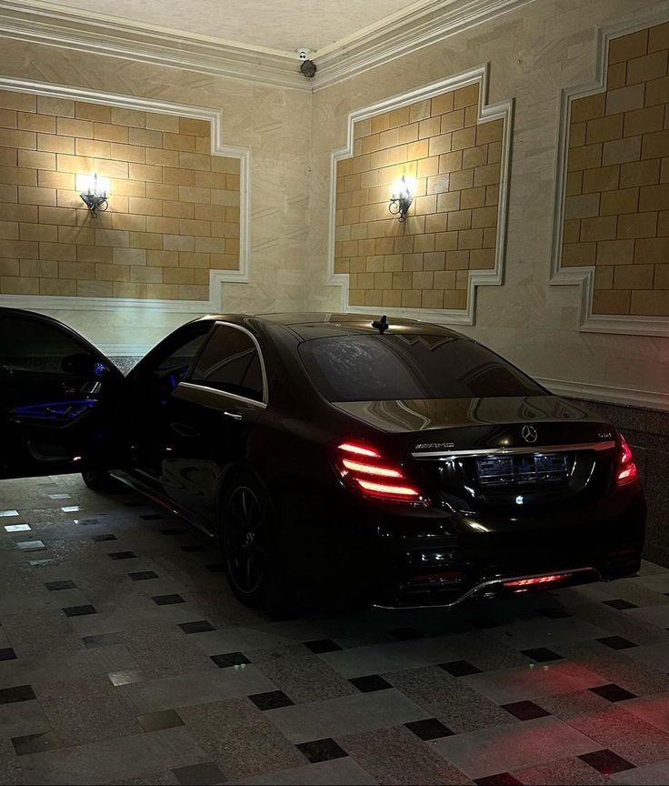 two cars are parked in the middle of a room with checkered tile flooring