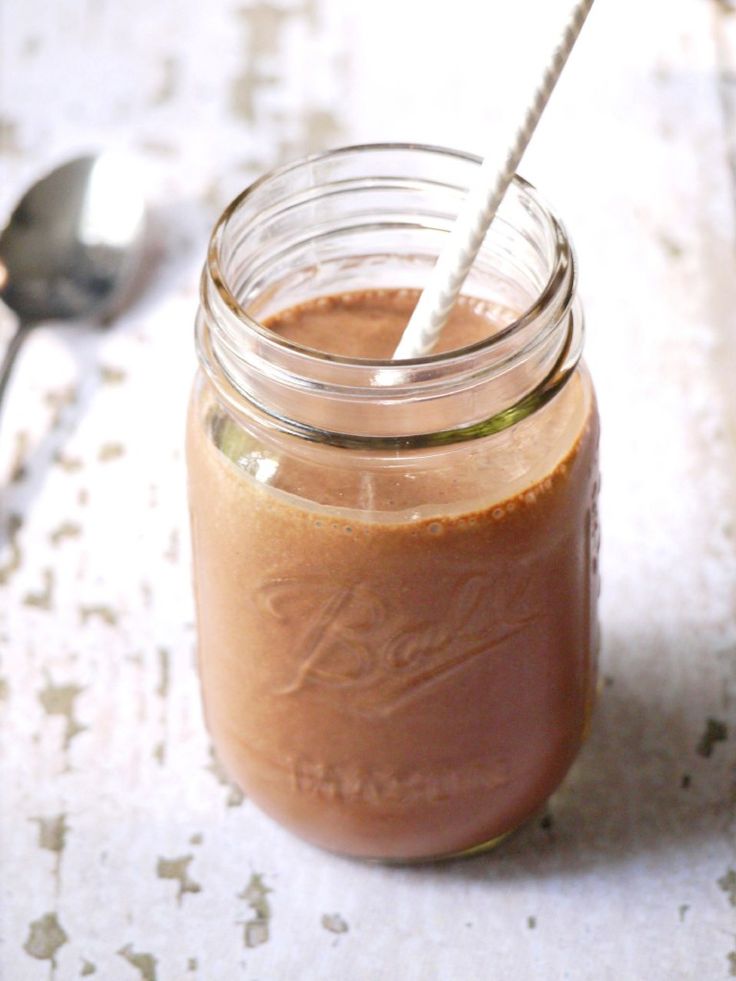 a glass jar filled with liquid sitting on top of a table next to a spoon