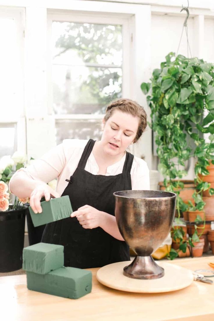 a woman in an apron is making something out of clay and wood block shapes on a table