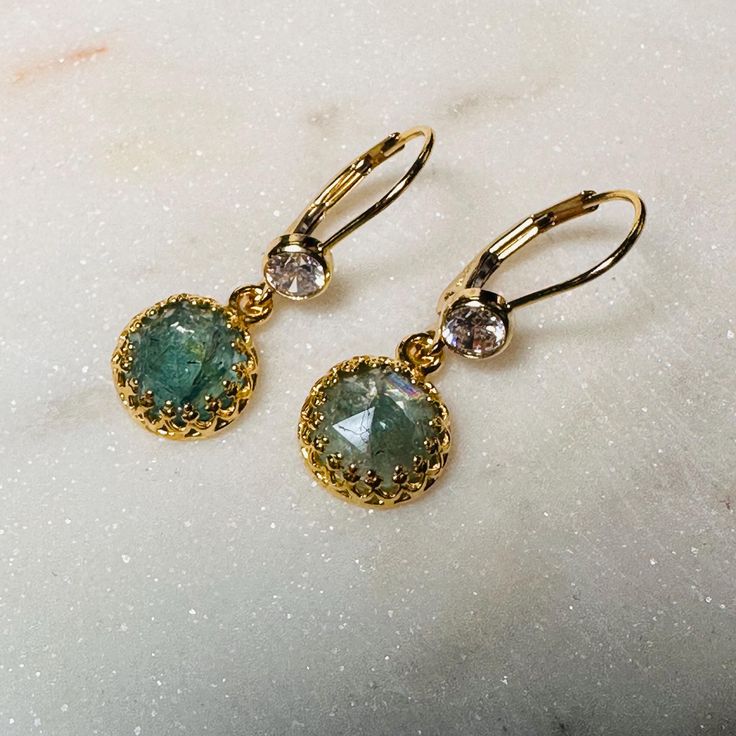 VERA EARRINGS These beautiful earrings are constructed in 14k Yellow gold filled. The bottom gemstone is an 8 mm round rose cut seafoam green Apatite set in a decorative tiara bezel.  On the lever back earring is a bezel set 4 mm round brilliant cut CZ. What does "Gold Filled" mean?  In contrast to gold plating, gold-filled jewelry is tarnish resistant and can last many years if properly maintained.  The manufacturing process for gold-filled metal is more complex than electroplating.  Unlike gold-plated materials, gold-filled jewelry retains the value of its gold content over time.  Gold plating can wear off quickly and expose the brass base product. It does not stand up to heat, water or wear over time. By comparison, gold-filled contains 5% gold alloy by weight. All the gold is on the su Gold Diamond Earrings For May Birthstone, Dainty Round Earrings For May Birthstone, 14k Gold Round Earrings For May Birthstone, Faceted Earrings For May Birthstone, Yellow Gold Earrings With Rose Cut Diamonds As Gift, Faceted 14k Gold Filled Yellow Gold Earrings, 14k Gold Faceted Earrings For Anniversary, Round Diamond Earrings For May Birthstone Gift, Round Rose Cut Diamond Earrings As Gift