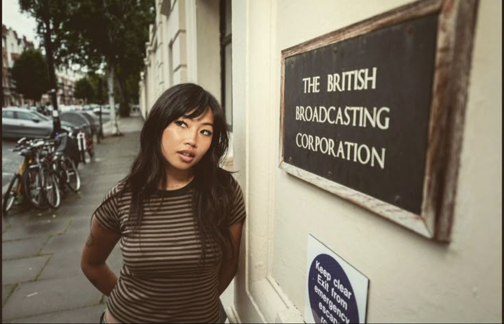 a woman standing next to a sign on the side of a building