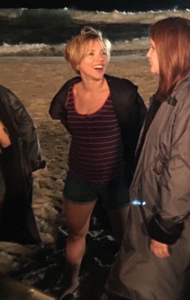 two women standing on the beach talking to each other