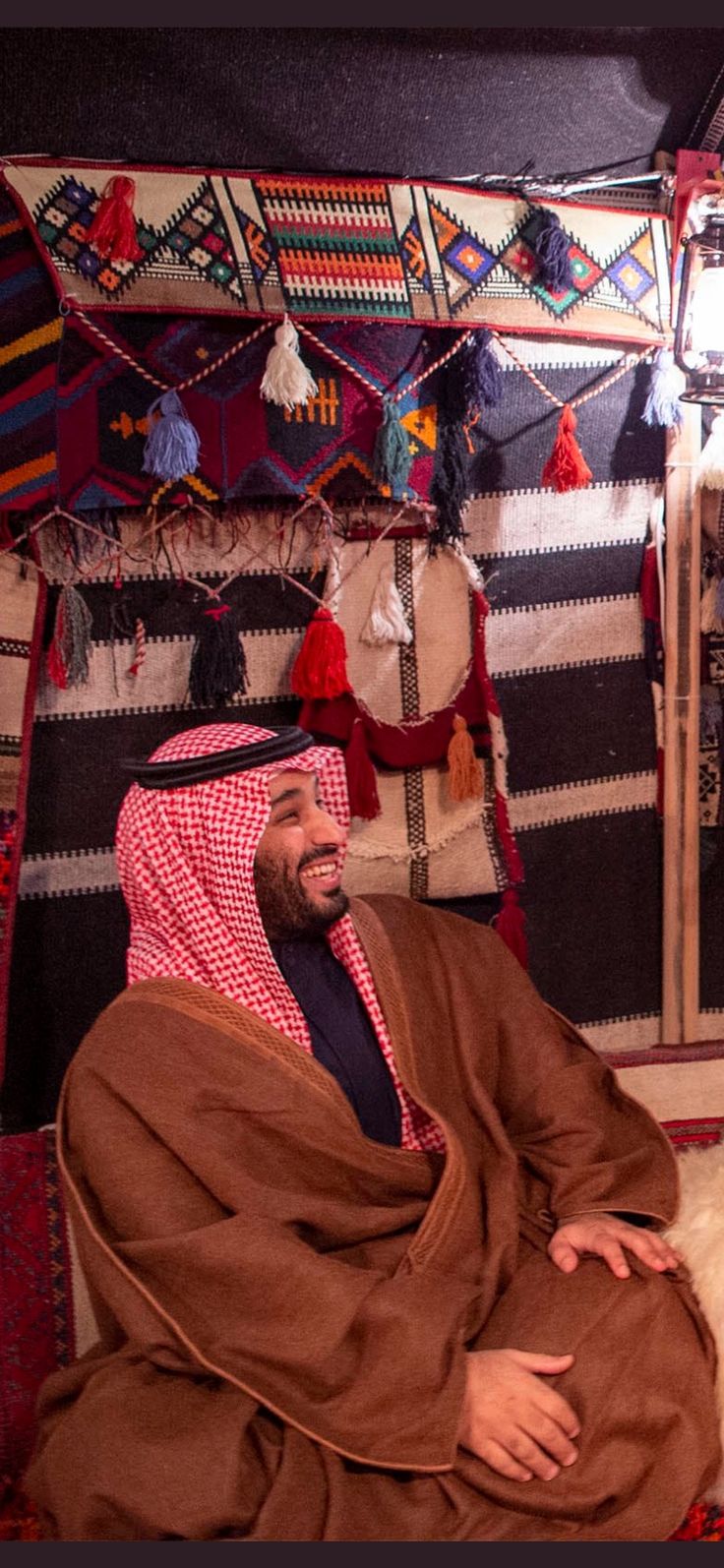 a man sitting on top of a bed in a room with lots of rugs