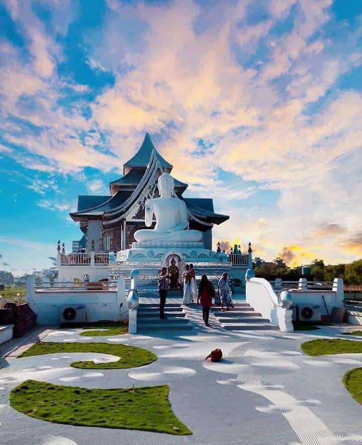 people are standing on the steps in front of a white building with green grass around it