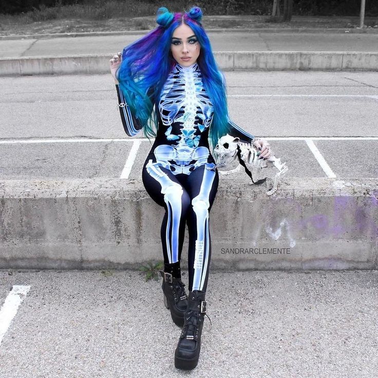 a woman with blue hair and skeleton makeup is sitting on the curb holding a baseball glove