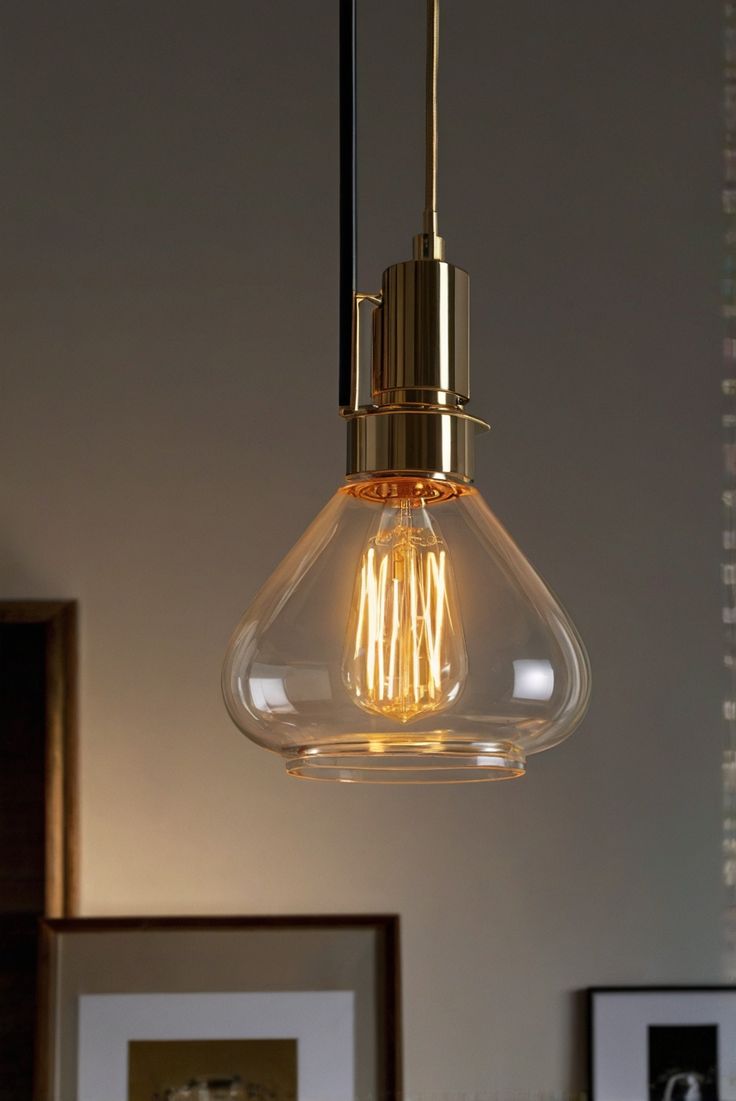 a light bulb hanging from the ceiling in a room with framed pictures on the wall