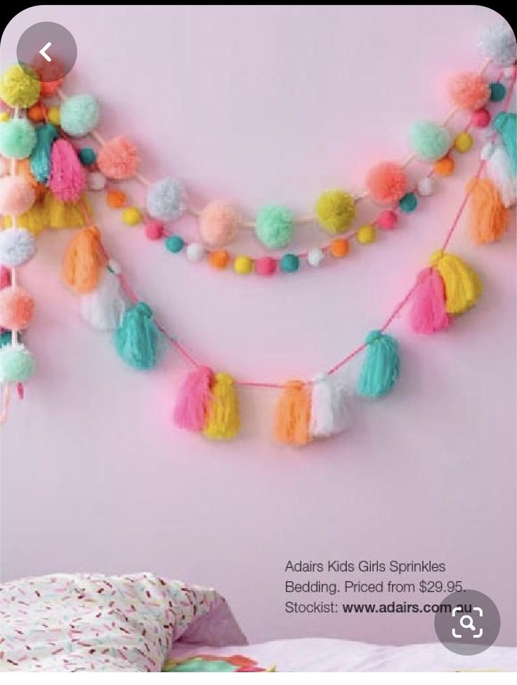 the wall is decorated with multicolored pom poms and tassels