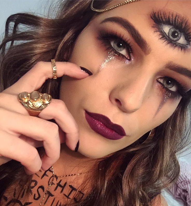 a close up of a person wearing makeup and holding a ring on her finger,