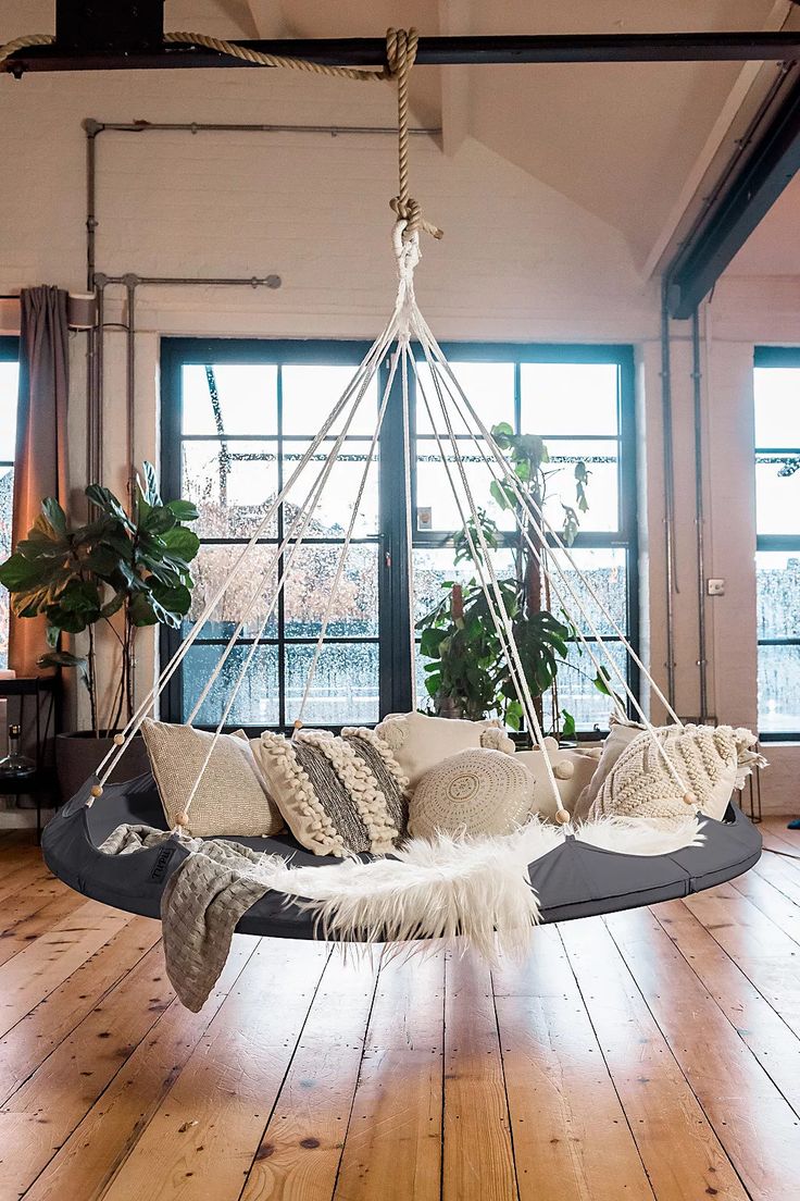 a living room with a hanging chair and potted plants