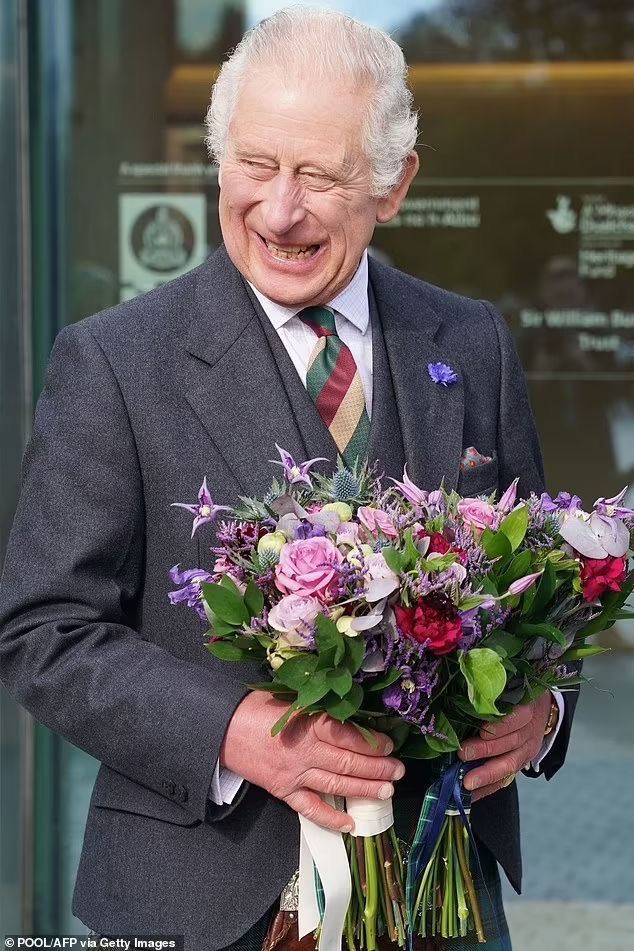 an older man in a suit and tie holding a bouquet of flowers while standing next to a building