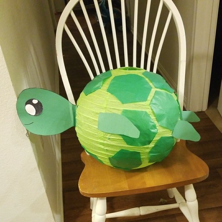 a paper plate turtle sitting on top of a wooden chair