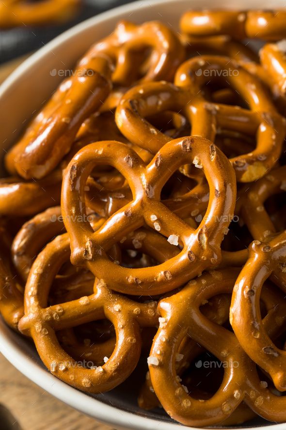 a bowl filled with pretzels on top of a wooden table - stock photo - images