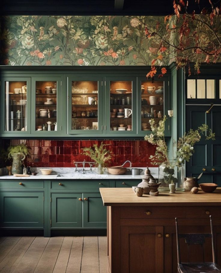 a kitchen with green cabinets and floral wallpaper on the walls, along with wooden flooring