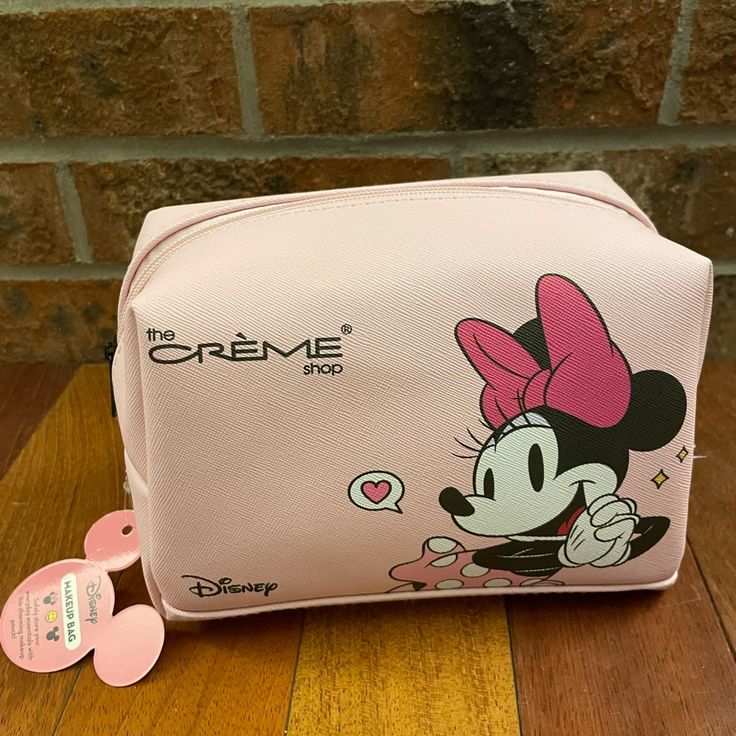 a pink mickey mouse purse sitting on top of a wooden table