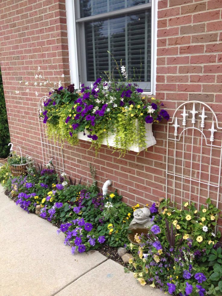 some purple and yellow flowers are growing in the window sill next to a brick building