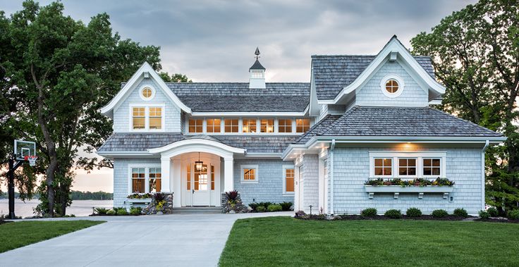 a blue house with white trim on the front and side windows is lit up at night