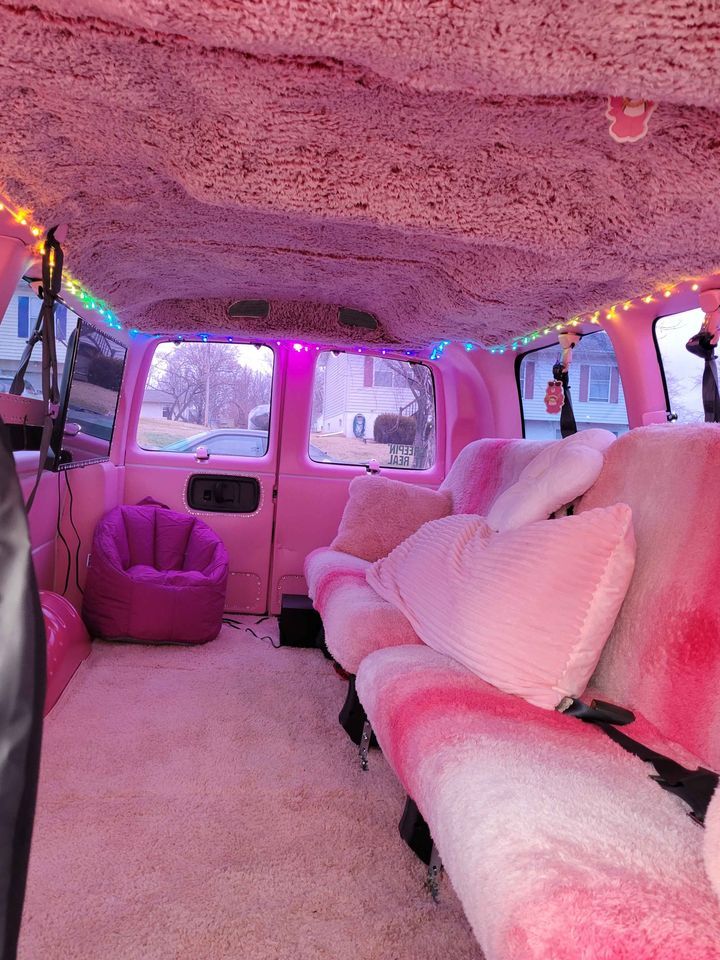 the interior of a vehicle with pink and white fur on the floor, couches, and lights