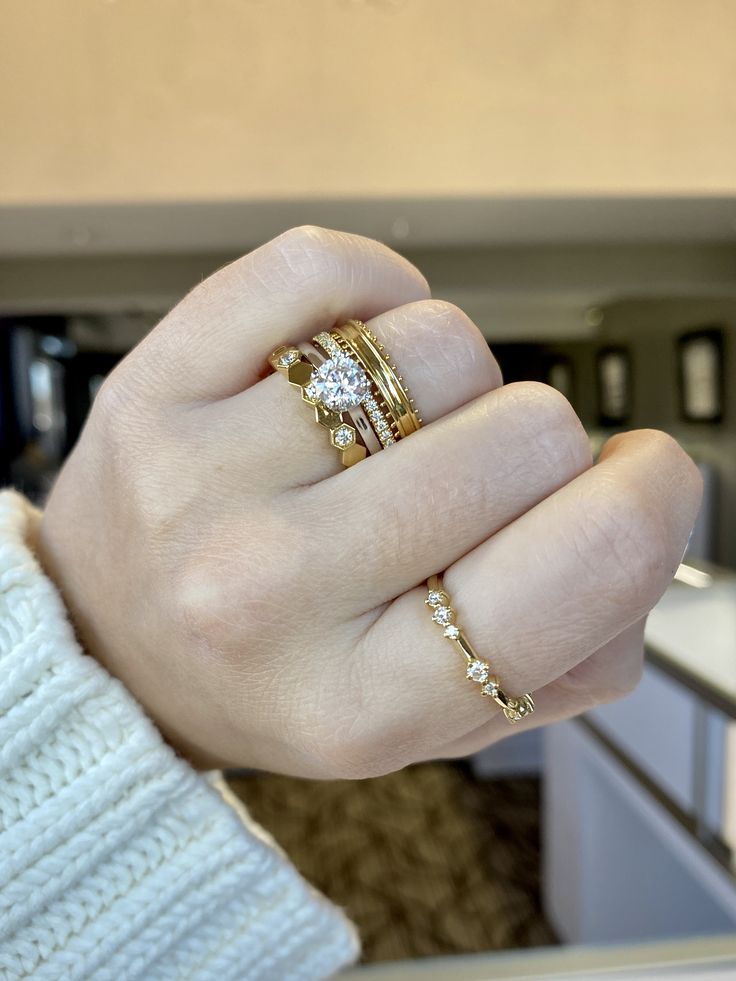 a woman's hand with two gold rings on it and one diamond ring in the middle