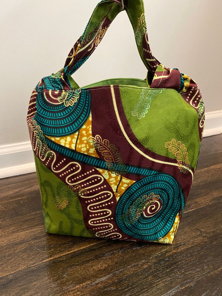 African Print Fabric! What a creative way to make a fashion statement with vibrant colors. This set comes with a handbag, small clutch bag, and a crossbody. All made with the same fabric.  The main colors are Lime Green, Teal, and Eggplant. Approximately measures: Clutch with clear handles: 6x11x5 Crossbody: 10 x 8 Handbag 10.5 x8x 4.5 They make really good gifts for friends and family. Washing: Spot cleaning is recommended. Measurements are approximate and may vary slightly with each purse sinc Green Rectangular Bucket Bag For Gifts, Green Rectangular Bucket Bag As Gift, Rectangular Green Bucket Bag As A Gift, Green Fabric Bag For Everyday Use, Everyday Green Fabric Bag, Everyday Green Fabric Bags, Reversible Multicolor Fabric Shoulder Bag, Multicolor Fabric Bag With Handles, Trendy Multicolor Fabric Shoulder Bag