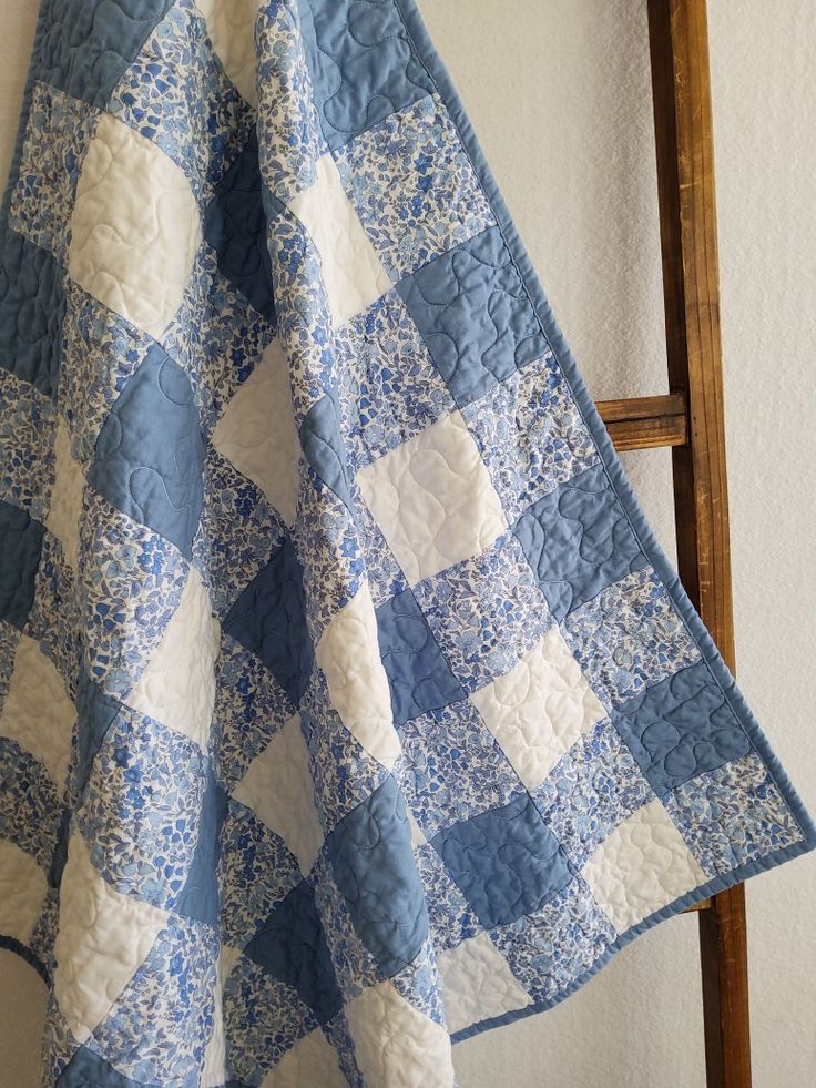 a blue and white checkered quilt hanging on a wall next to a wooden chair