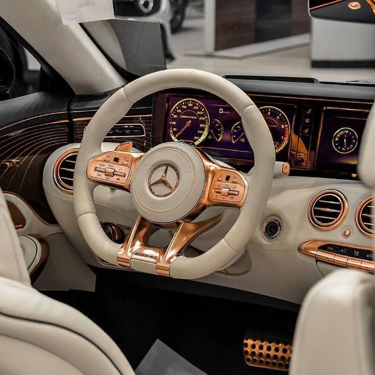 the interior of a luxury car with gold trims and steering wheel, dash lights