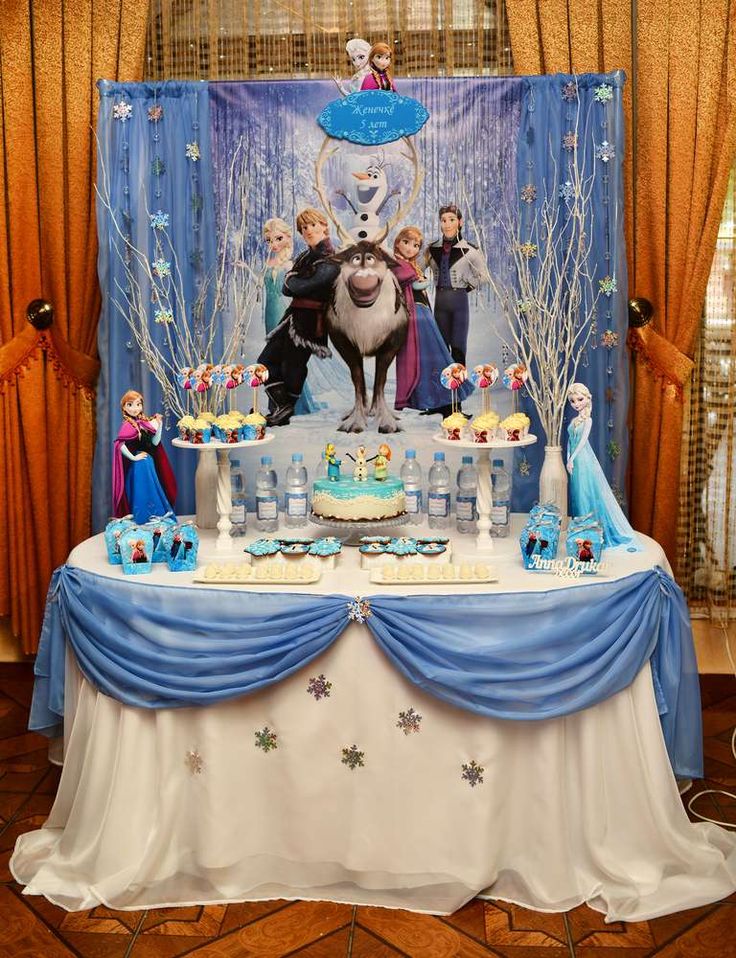 the table is decorated with cupcakes, cake and decorations for a frozen world birthday party