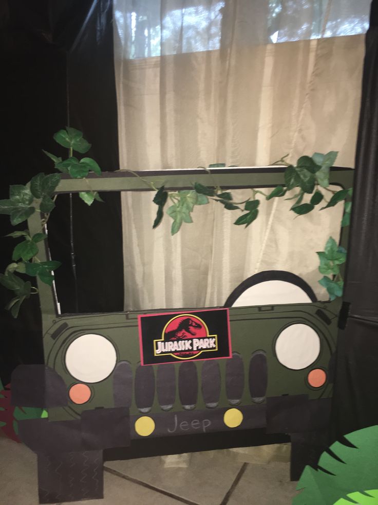 a cardboard jeep is sitting in front of a window with plants growing out of it