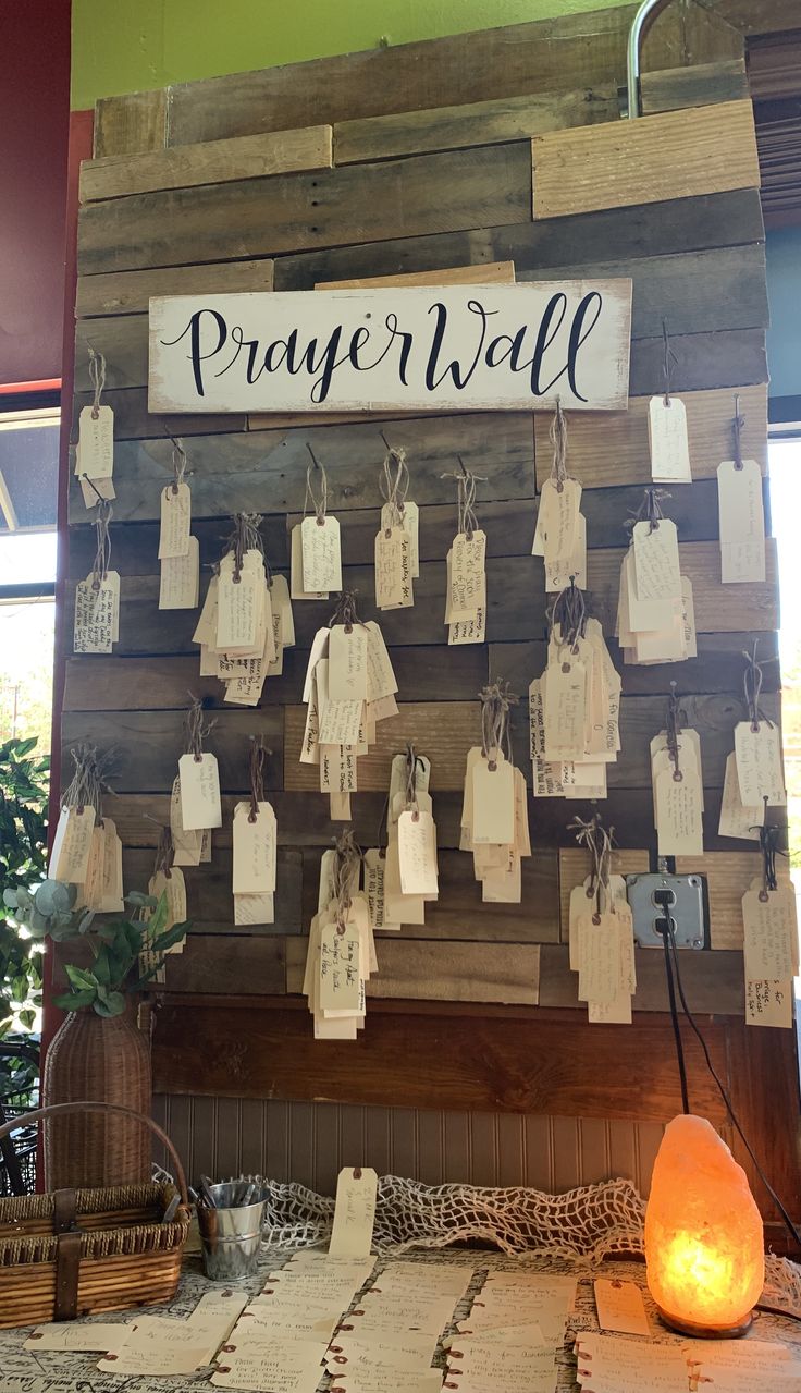 a wooden wall with many tags hanging from it's sides and the word prayer hall written on them