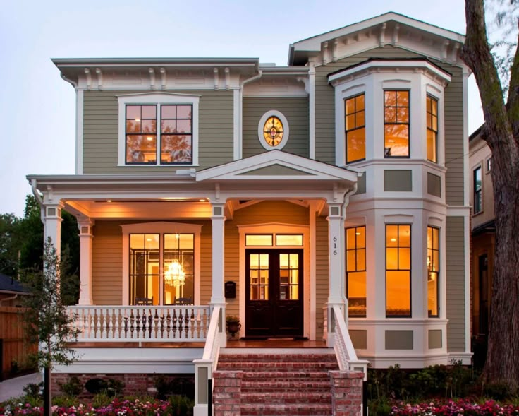 a large house with many windows and steps leading up to the front door that is lit up at night