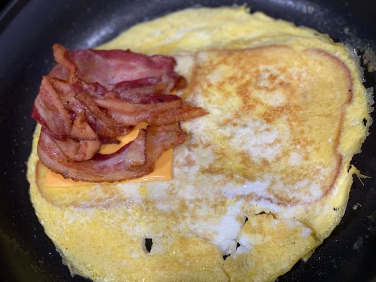 an omelet with bacon and cheese in a skillet