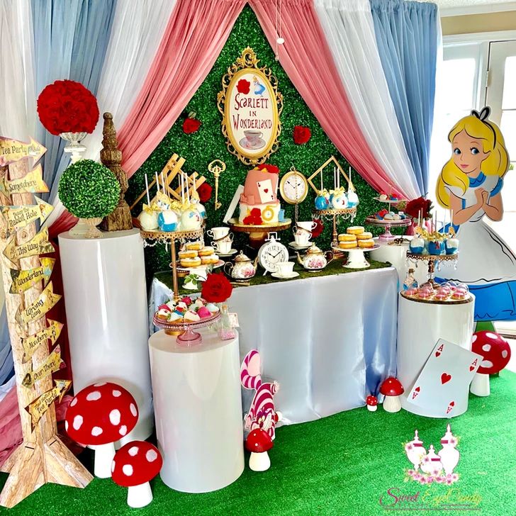 the table is set up for an alice in wonderland birthday party with lots of food and decorations