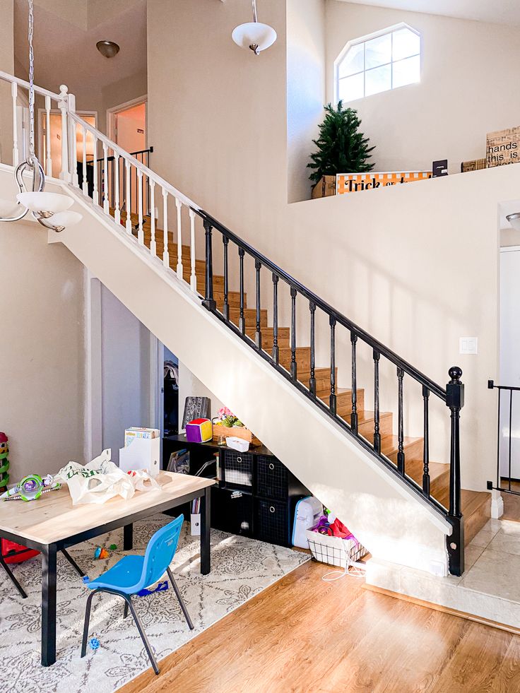 a room with a table and chairs under a stair case next to a staircase leading up to the second floor