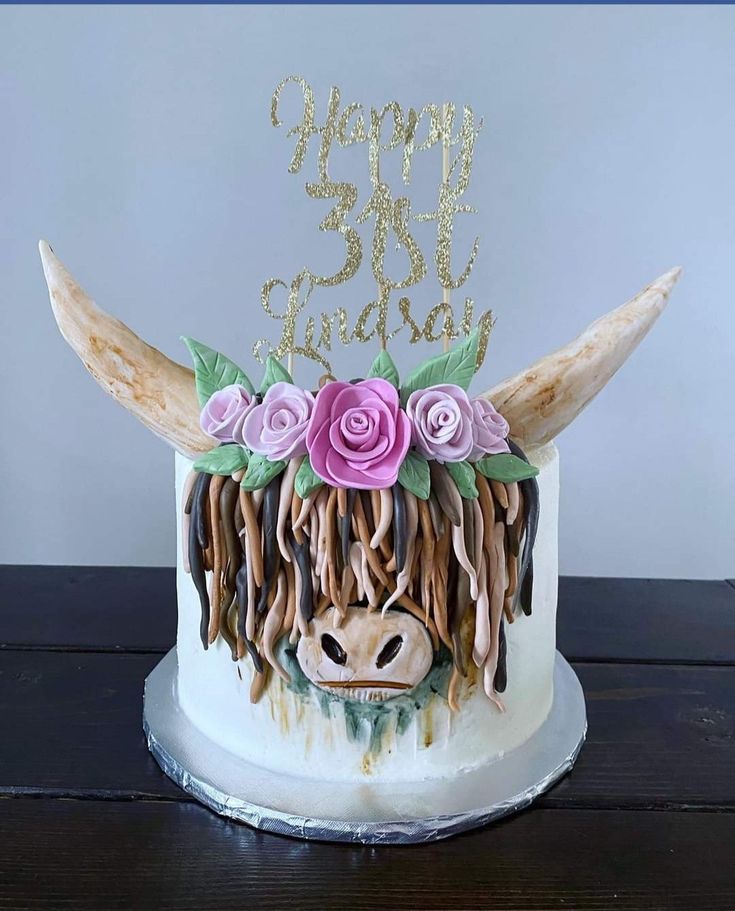 a cake decorated with flowers and an animal's head is on a wooden table