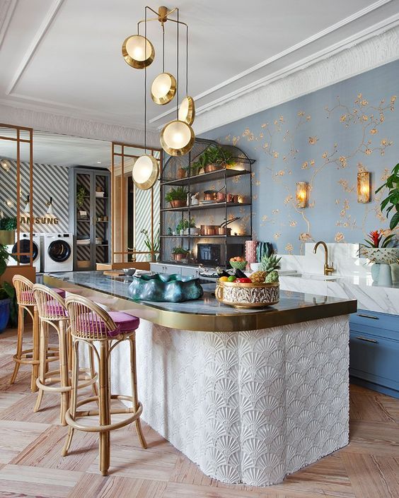 a kitchen with blue walls and gold trimmings on the counter top, surrounded by bar stools