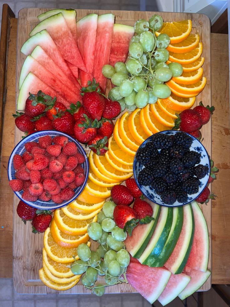 a wooden cutting board topped with lots of fruit and veggie platters next to each other