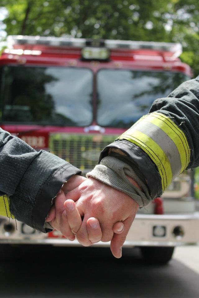 two people shaking hands in front of a fire truck