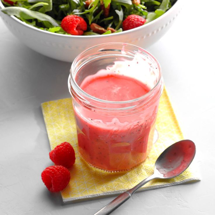 a bowl of salad with raspberries next to it