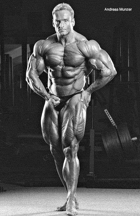 a man standing in the middle of a gym with his hands on his hips and muscles showing