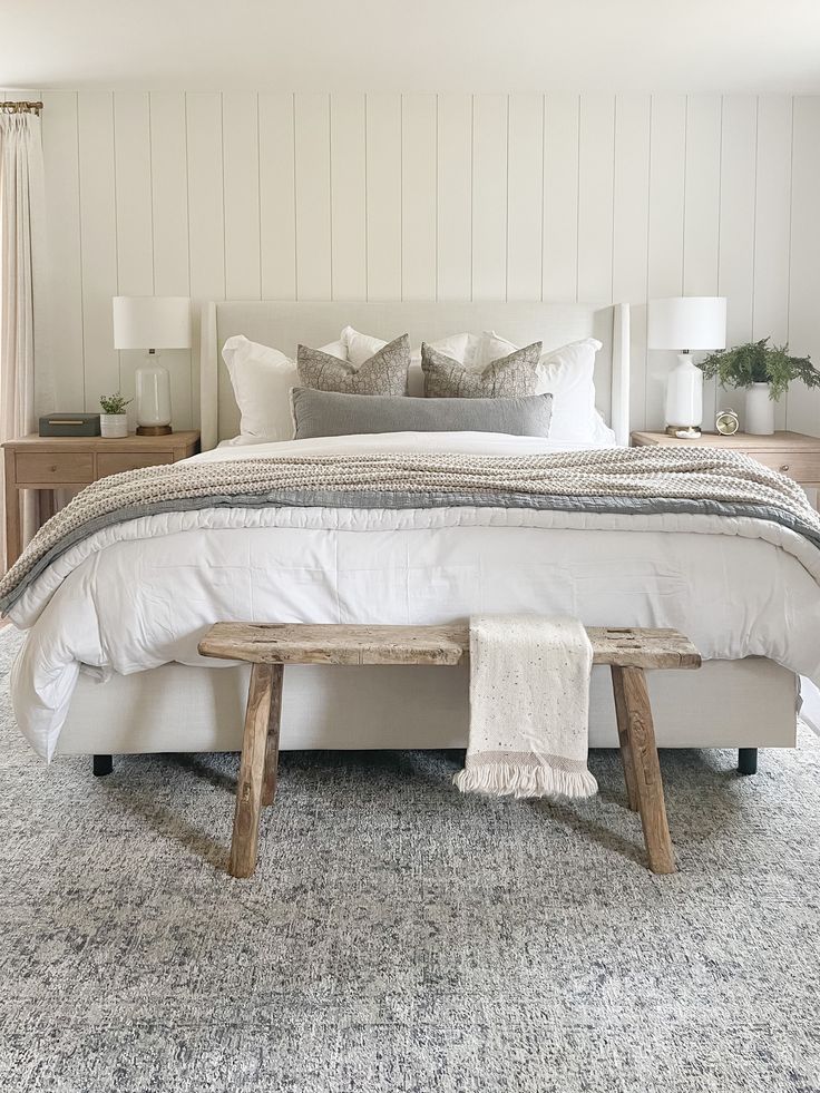 a white bed with two wooden benches in front of it