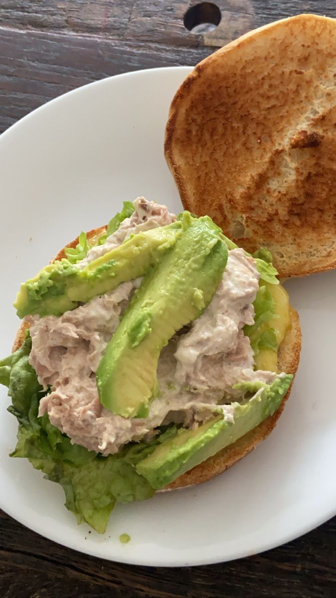 a sandwich with meat and lettuce on a white plate next to a piece of bread