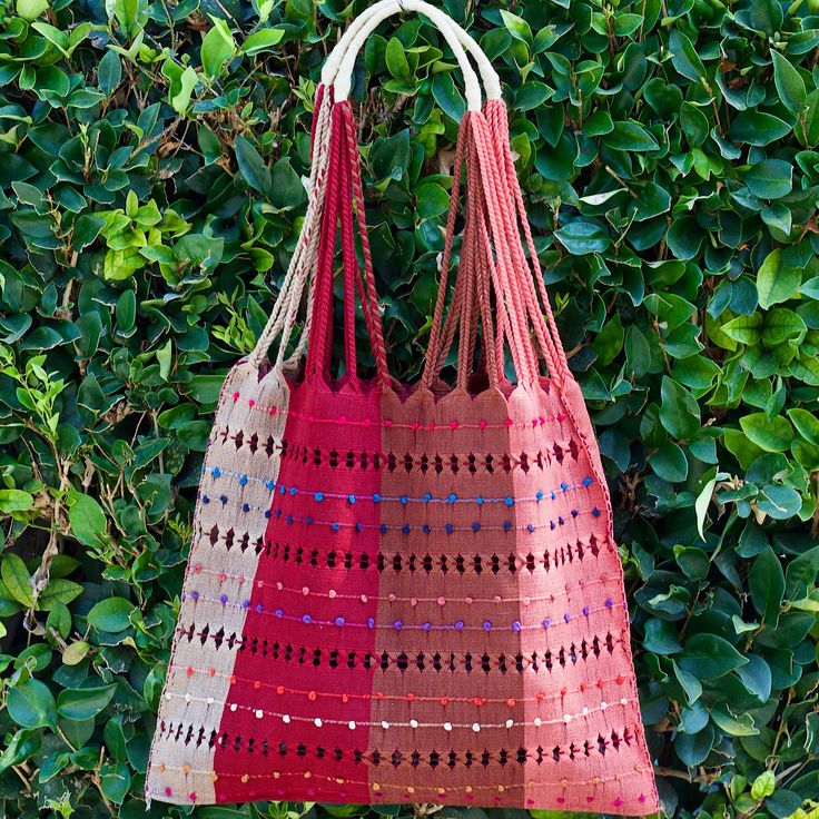 a red bag hanging from the side of a bush