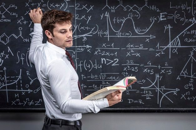 a man standing in front of a blackboard with writing on it