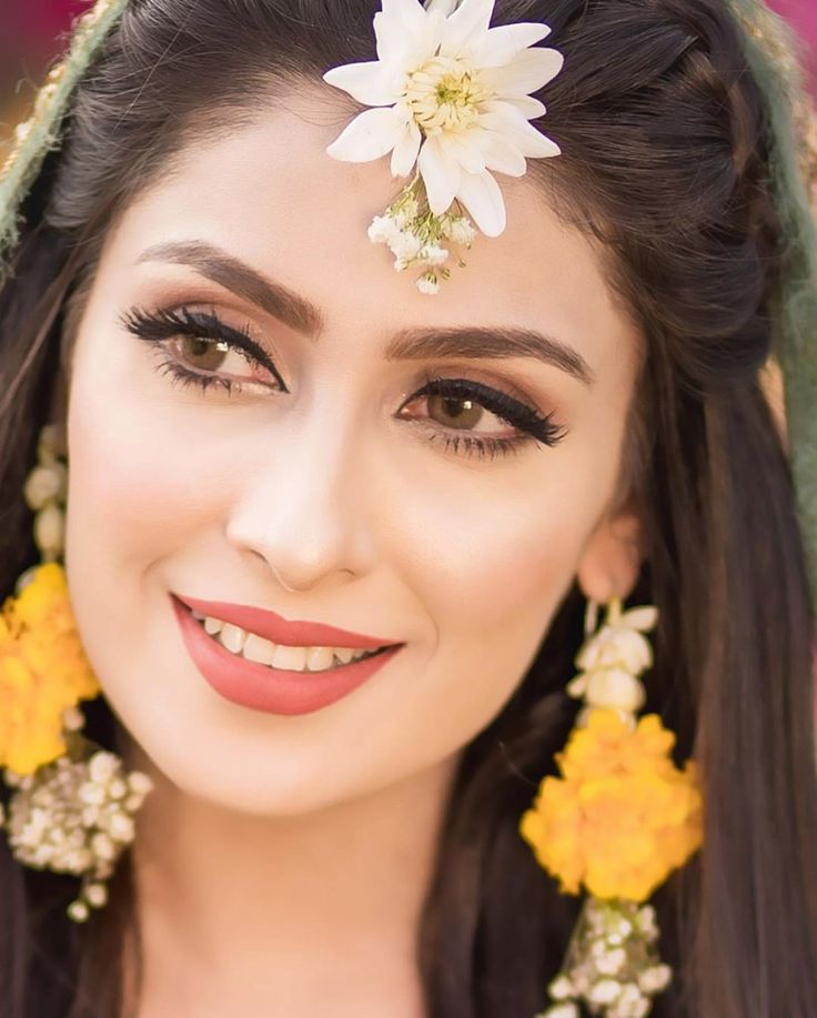 a woman with flowers in her hair smiling at the camera and wearing earrings on her head