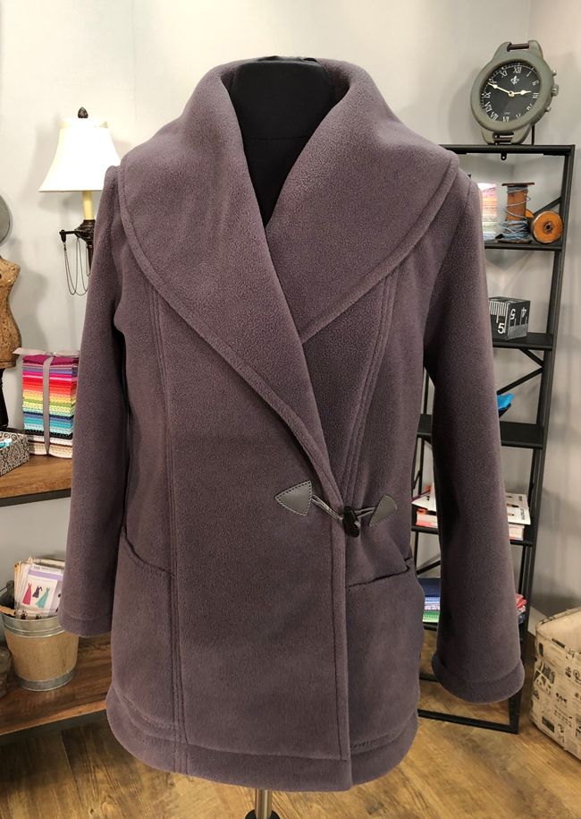 a purple coat is sitting on a mannequin's head stand in a room