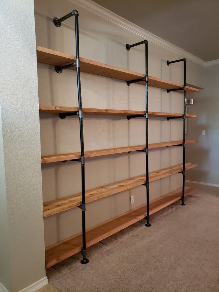 an empty room with some shelves and pipes on the wall in front of it, next to a carpeted floor