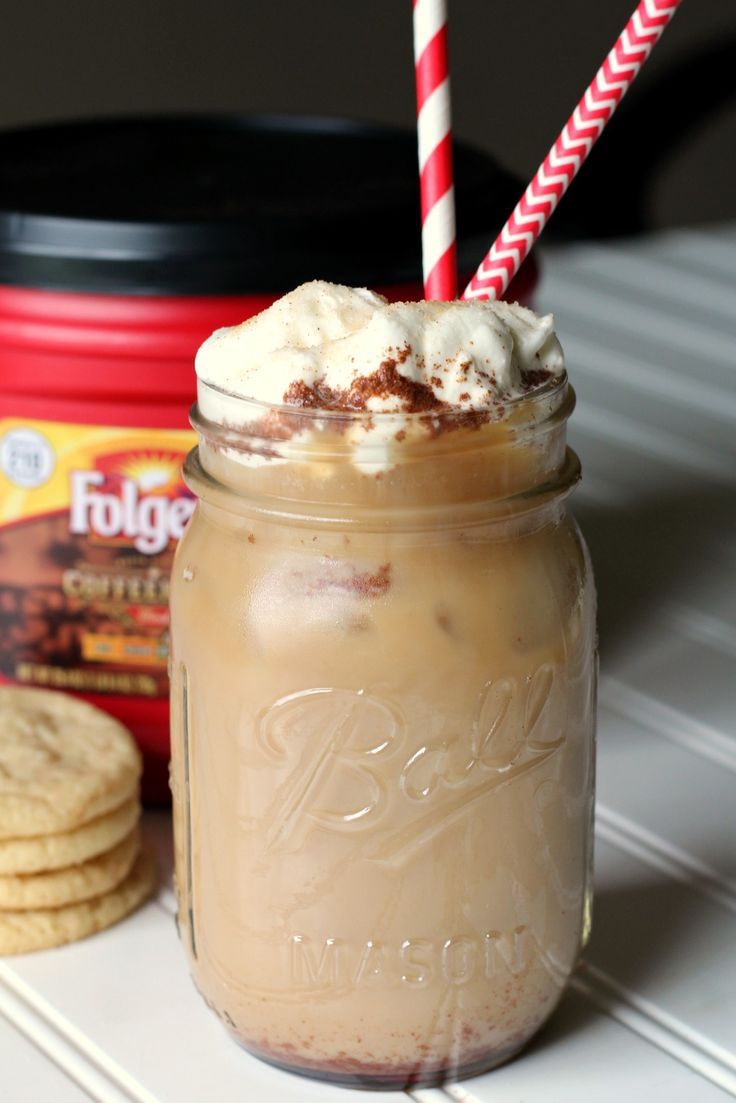 there is a drink in a mason jar with whipped cream and cookies on the side